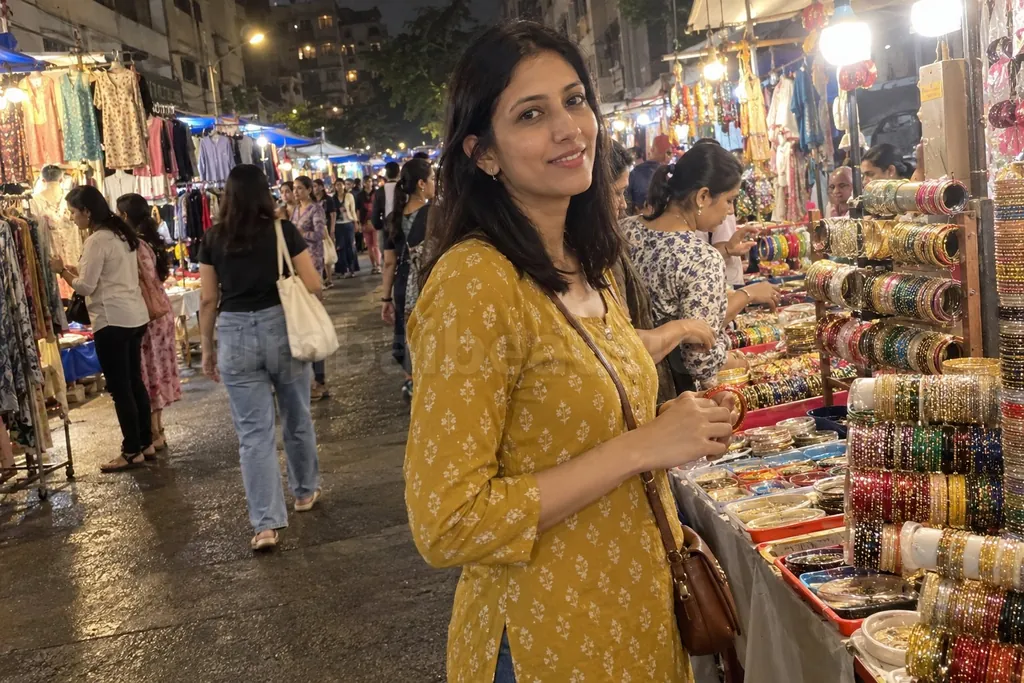 Call girls in Andheri: a woman in a printed kurta picks bangles at a Lokhandwala market stall at night