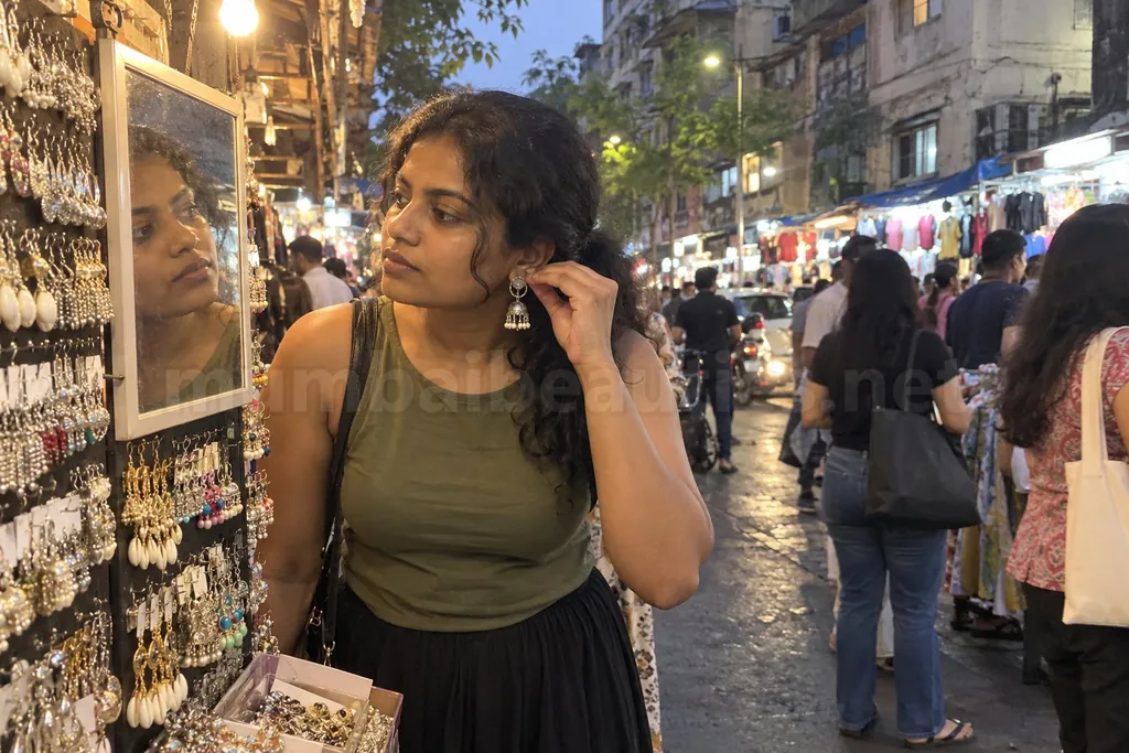 Bandra escorts: a woman picks earrings at a Hill Road street stall in the evening